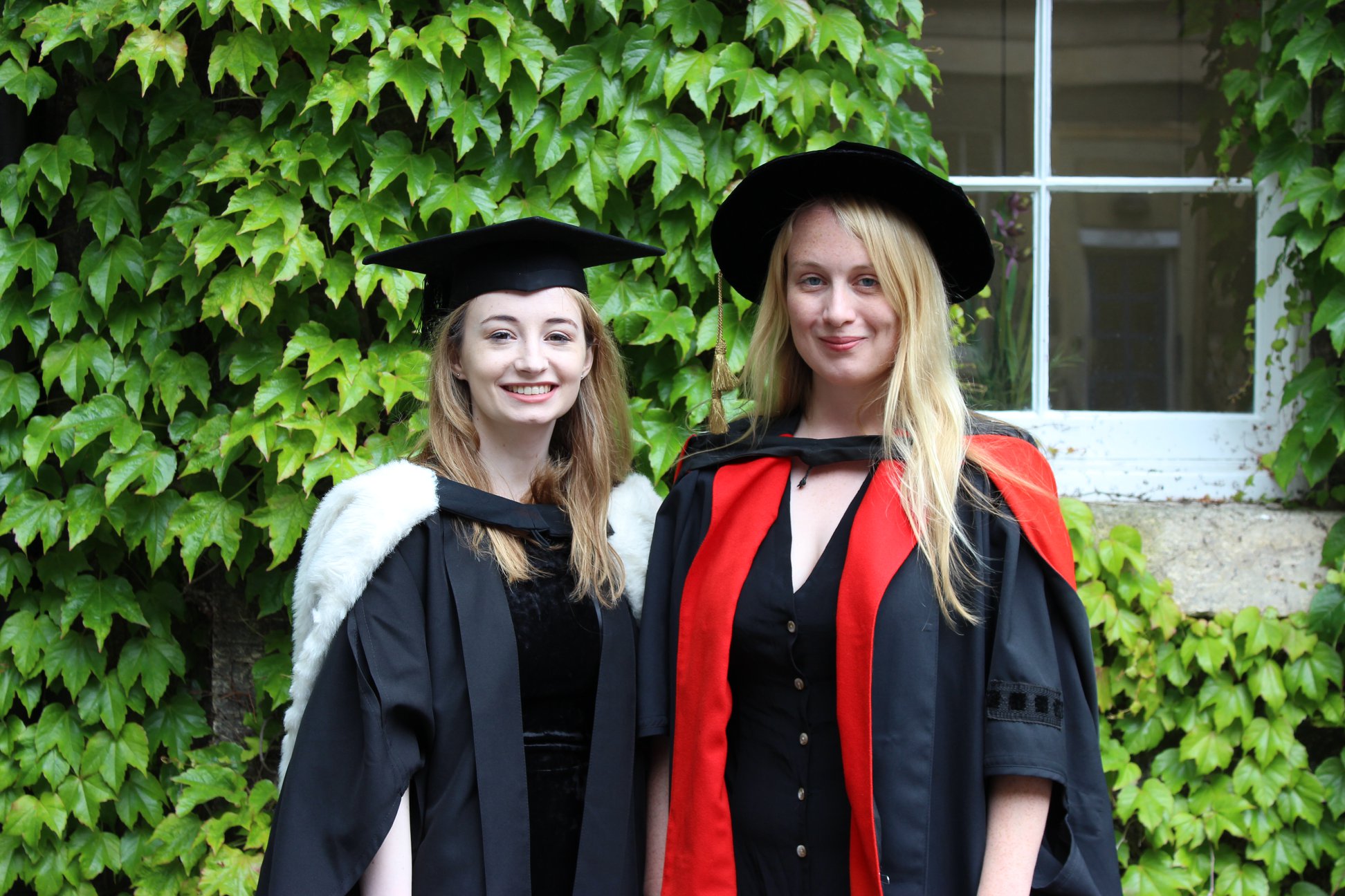 Two people wearing Graduation Gowns, smiling.