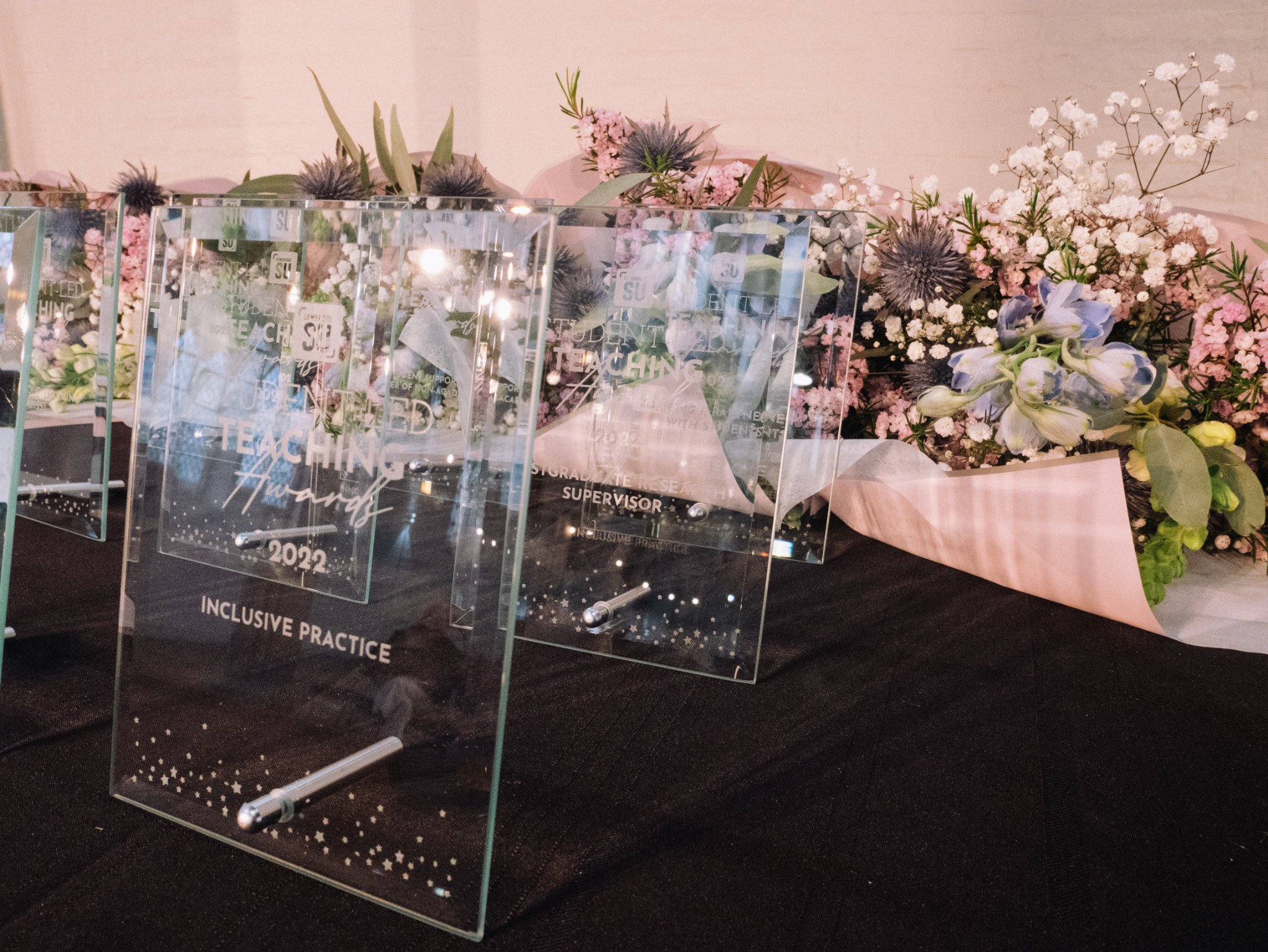 SLTA awards are placed on a table with flowers behind them for award winners